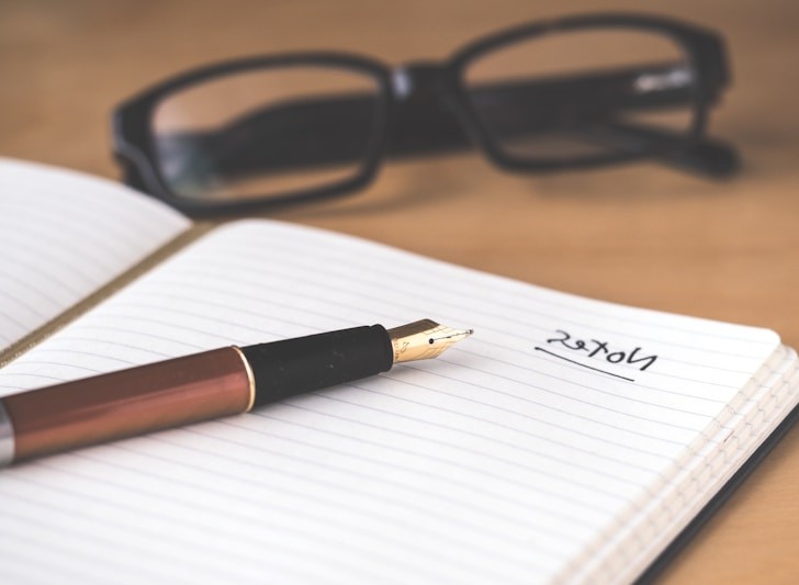 Open notebook with handwritten notes and pen on desk